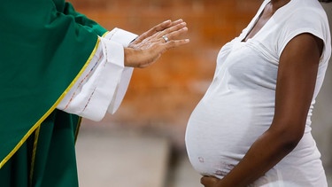 Die Hände eines Pfarrers über dem Bauch einer Schwangeren. | Bild: picture alliance/dpa | Jesus Vargas I SYMBOLBILD