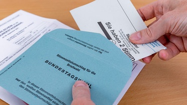 Ein Mann steckt seinen gefalteten Stimmzettel in den dafür vorgesehenen Stimmzettelumschlag (Symbolbild). | Bild: pa/Stephan Goerlich