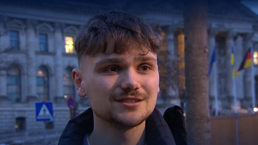 Der 23-jährige Luke Hoß aus Passau, Deutschlands jüngster Bundestagsabgeordneter, steht vor dem Deutschen Bundestag in Berlin.  | Bild: Screenshot BR/ARD Brennpunkt