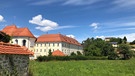 Ein Klostergebäude mit hellen Wänden und rotem Ziegeldach von außen. | Bild: Bauwärts