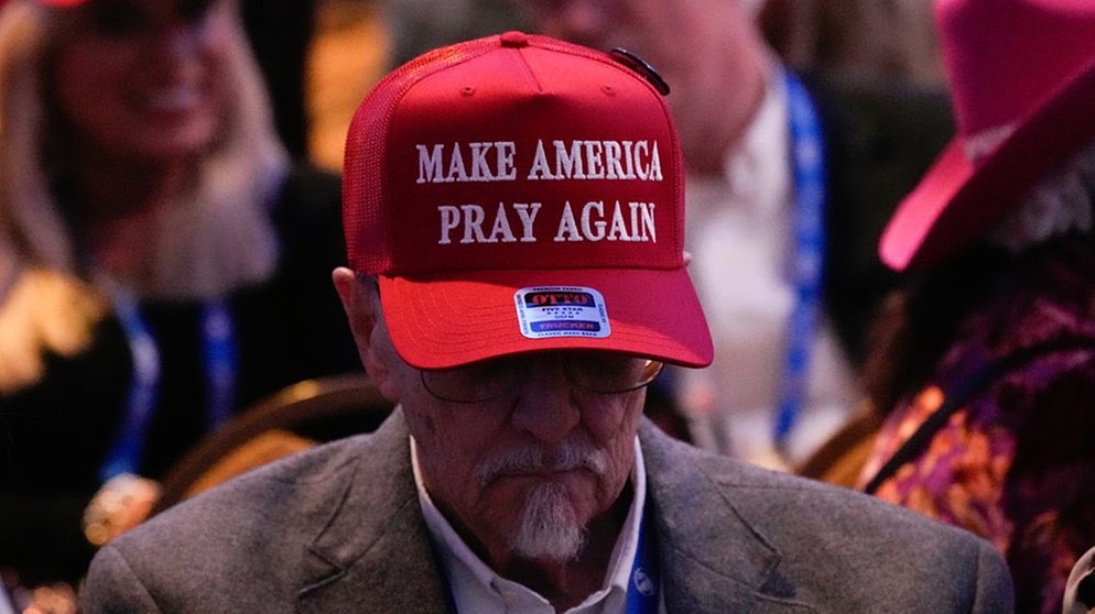 Mann mit einer roten Baseball-Kappe mit der Aufschrift "Make America Pray Again" | Bild: picture alliance / ASSOCIATED PRESS | George Walker IV