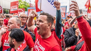 Wütende Männer recken Fäuste in die Lüfte: Demonstration von Stahlarbeitern vor der Firmenzentrale von ThyssenKrupp in Essen am 23.05.2024 | Bild: picture alliance / Jochen Tack | Jochen Tack