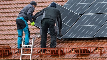 Zwei Männer installieren eine PV-Anlage in Markt Schwaben | Bild: picture alliance / Stephan Goerlich