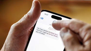 Ein älterer Mann blickt auf sein Smartphone, auf dem er von einer unbekannten Nummer eine Nachricht erhalten hat. | Bild: picture alliance / dpa | Matthias Balk