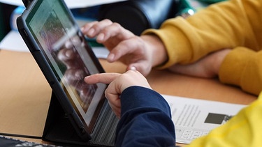 Schüler sitzen während des Unterrichts an einem Tablet.  | Bild: dpa-Bildfunk/Soeren Stache