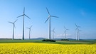 Windkrafträder hinter einem gelben Rapsfeld vor blauem Himmel. | Bild: stock.adobe.com/elxeneize
