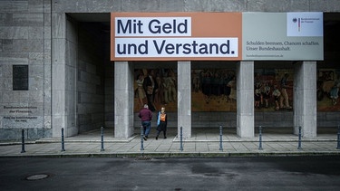 Ein Plakat mit der Aufschrift "Mit Geld und Verstand. Schulden bremsen, Chancen schaffen. Unser Bundeshaushalt." hängt über dem Eingang zum Bundesministerium der Finanzen in Berlin. | Bild: dpa-Bildfunk/Kay Nietfeld