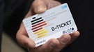 Eine Person hält ein Deutschlandticket in der Hand.  | Bild: dpa-Bildfunk/Boris Roessler