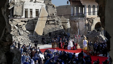 Papst Franziskus, umgeben von den Ruinen zerstörter Kirchen, betet für die Opfer des Krieges auf dem Hosh al-Bieaa-Kirchenplatz in Mosul 2021. | Bild: picture alliance / ASSOCIATED PRESS | Andrew Medichini