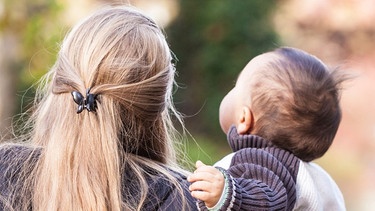 Eine Mutter hält ihr Kind auf dem Arm. | Bild: stock.adobe.com/Lilli