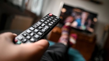 Ein junger Mann sitzt mit einer Fernbedienung vor dem Fernseher. | Bild: dpa-Bildfunk/Britta Pedersen