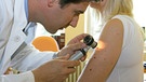 Ein Dermatologe untersucht eine Patientin auf Anzeichen von Hautkrebs.  | Bild: picture-alliance / Bildagentur-online/PWI-McPhoto |