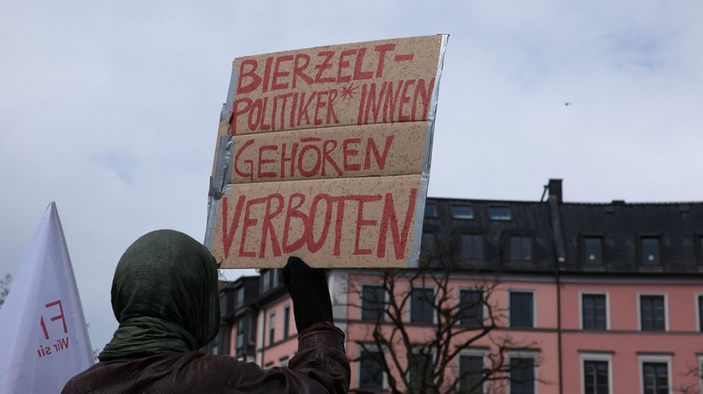 Ein Demonstrant hält ein Plakat bei einer Demonstration hoch, auf dem steht: Bierzeltpolitikerinnen gehören verboten. Vor dem "innen" ist ein Gender-Sternchen gesetzt | Bild: picture alliance / SZ Photo | Florian Peljak