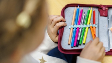 Ein kleines Mädchen nimmt einen Stift aus seinem Etui. | Bild: picture alliance / dpa | Matthias Balk