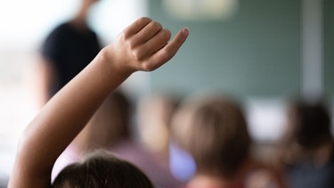 Schülerinnen und Schüler der vierten Klasse einer Grundschule nehmen am Unterricht teil, eine Schülerin meldet sich. | Bild: picture alliance/dpa | Marijan Murat