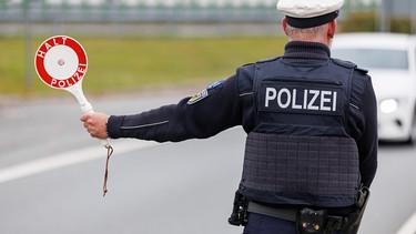 ARCHIV - 18.10.2023, Bayern, Furth im Wald: Ein Beamter der Bundespolizei stoppt bei der Kontrolle des Einreiseverkehrs am deutsch-tschechischen Grenzübergang Furth im Wald - Ceska Kubice den Fahrer eines Autos bei der Einreise. (zu dpa: «Schlag gegen mutmaßliche Schleuserbande - drei Festnahmen») Foto: Daniel Karmann/dpa +++ dpa-Bildfunk +++ | Bild: dpa-Bildfunk/Daniel Karmann