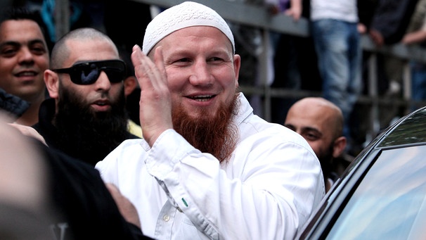 Abgeschirmt durch seine Begleiter verlässt der salafistische Prediger Pierre Vogel am Samstag (09.07.2011) am Bahnhof Dammtor in Hamburg eine Kundgebung. | Bild: picture-alliance/dpa/Bodo Marks