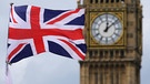 Eine britische Fahne weht in London, Großbritannien, vor dem berühmten Uhrturm Big Ben. Die Uhr auf dem Urm zeigt einige Minuten nach Zwölf an. | Bild: picture-alliance/dpa
