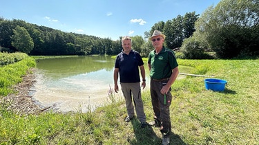 Teichwirt Norbert Reckenberger und Otto Müller von der Teichgenossenschaft Mittelfranken an einem Karpfenweiher in Bergtheim im Landkreis Neustadt/Aisch-Bad Windsheim. | Bild: BR24/Laura Fischer-Grun