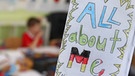 Von Schülerinnen und Schülern der Klasse 4b auf englisch gestaltete persönliche Heftchen hängen während des Unterrichtes in einem Klassenzimmer der Sankt Anna Grundschule in Augsburg an einer Leine. | Bild: picture-alliance/dpa