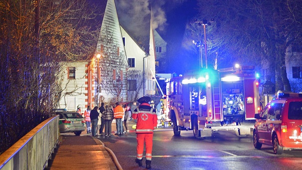 Feuerwehrfahrzeuge stehen in der Nacht zum 12.12.2014 in Vorra (Landkreis Nürnberger Land) vor einem brennenden Haus. In den drei als Flüchtlingsunterkunft vorgesehenen Gebäuden hatte es gebrannt. | Bild: picture-alliance/dpa