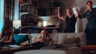 Von links: Zoe (Lena Klenke) und Milli (Clara Vogt) sitzen auf der Couch, während Caro (Silke Bodenbender) und Martin (Fabian Hinrichs) tanzen. | Bild: BR/Hager Moss Film GmbH/Luis Zeno Kuhn