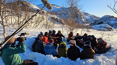 Verschnaufpause: Nach den ersten harten Kilometern auf Skiern gönnt sich die Klasse eine Brotzeit in einer selbst ausgehobenen Schneegrube | Bild: BR/Bewegte Zeiten Filmproduktion GmbH/Megan Ehrmann