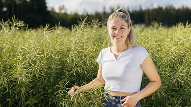 Landfrau Anna-Maria Stürzer steht vor einem Wald und schaut in die Kamera. | Bild: BR/megaherz gmbh/Hans-Florian Hopfner