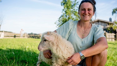 Anja steht mit ihrem kleinen Schaf auf einer Wiese. | Bild: BR/megaherz gmbh/Moritz Sonntag