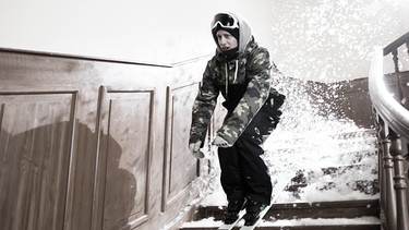 Freeskier Lukas Joas fährt mit seinen Ski die Treppe runter.  | Bild: BR/Markus Konvalin 