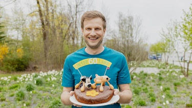 Florian Kienast mit der Jubiläumstorte. | Bild: BR/Leah Tanzer