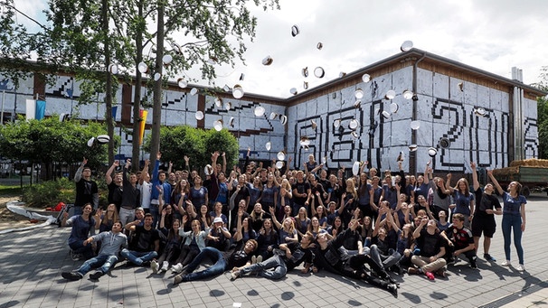 Abiturienten sitzen am 20.06.2016 im oberbayerischen Kirchseeon (Bayern) vor ihrer mit Papier komplett verklebten Schule. In einer Nacht- und Nebelaktion hatten sie die Fassade ihrer Schule verhüllt und protestieren so gegen die Papierverschwendung in Zeiten des Klimawandels. | Bild: picture-alliance/dpa