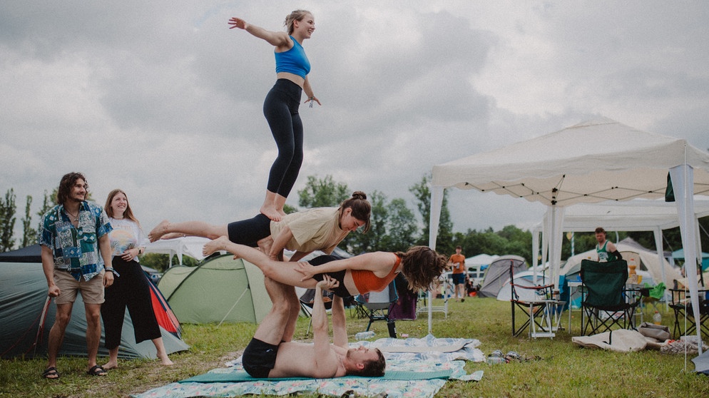 Vier Festivalbesucher:innen beim Acro-Yoga auf dem Festival.  | Bild: BR/Julia Knoblauch