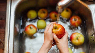 Frau wäscht Äpfel in Spühle | Bild: mauritius images / Westend61 / Nicole Matthews