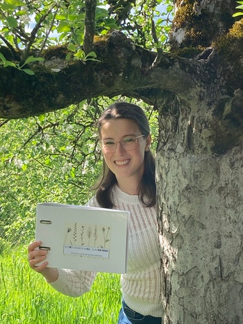 Eine junge Frau steht unter einem Baum und hält ihr eigenes Kochbuch in den Händen. | Bild: privat