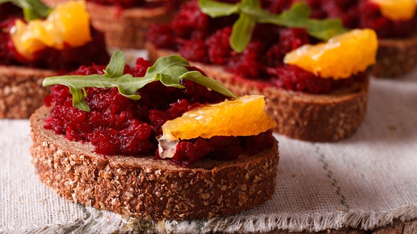 Bruschetta auf dunklem Brot mit Roter Bete, einem Blatt Rucola und einem Stück Orange | Bild: mauritius images / Alamy / Sergii Koval