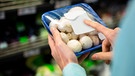 Frau hält in einem Supermarkt eine Packung mit Champignons in der Hand | Bild: mauritius images / Wavebreak Media ltd / Alamy / Alamy Stock Photos