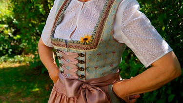 Eine Frau im Dirndl stützt die Hände in die Hüfte | Bild: mauritius images / Julia Färber / Alamy / Alamy Stock Photos