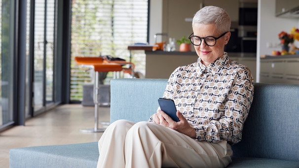 Frau im mittleren Alter liest Mails auf ihrem Smartphone | Bild: mauritius images / Westend61 / Rainer Berg