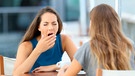 Frau sitzt mit einer Freundin in einem Straßencafé und gähnt | Bild: mauritius images / Antonio Guillem Fernández / Alamy / Alamy Stock Photos