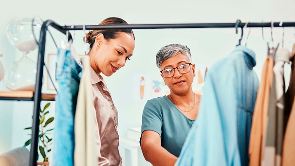 Frauen in einem Modegeschäft sehen sich Kleidung an | Bild: mauritius images / Yuri Arcurs / Alamy / Alamy Stock Fotos