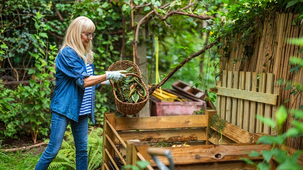 Frau wirft Gartenabfälle auf einen Komposthaufen | Bild: mauritius images / Pikselstock / Alamy / Alamy Stock Photos