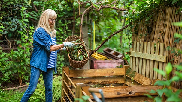 Frau wirft Gartenabfälle auf einen Komposthaufen | Bild: mauritius images / Pikselstock / Alamy / Alamy Stock Photos