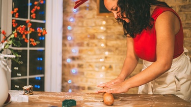 Frau rollt Plätzchenteig für die Weihnachtsbäckerei aus | Bild: mauritius images / Connect Images / Bonfanti Diego