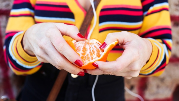 Frauenhände schälen eine Mandarine | Bild: mauritius images / Westend61 / Retales Botijero