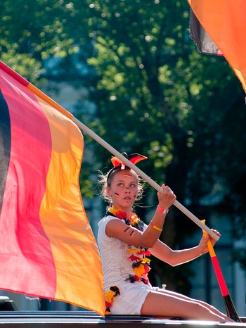Frau schwenkt Deutschland-Fahne zu einem Fußballspiel | Bild: mauritius images /
AM Stock 2 / Alamy / Alamy Stock Photos
