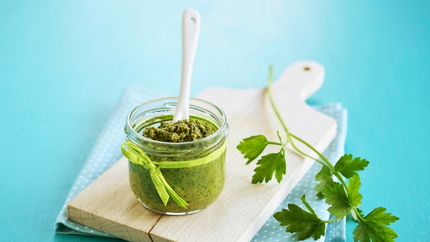 Ein Glas mit selbstgemachtem Pesto aus Petersilie steht auf einem Holzbrett | Bild: mauritius images / foodcollection