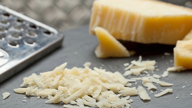 Gehobelter Grana Padano und eine Käsereibe | Bild: mauritius images / foodcollection