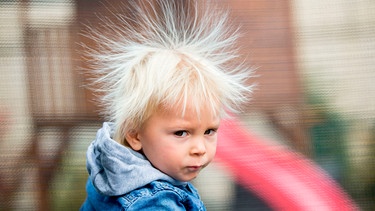 Ein Junge, dessen Haare statisch aufgeladen sind und nach oben stehen, in einem Trampolin | Bild: mauritius images / Tatyana Tomsickova / Alamy / Alamy Stock Photos