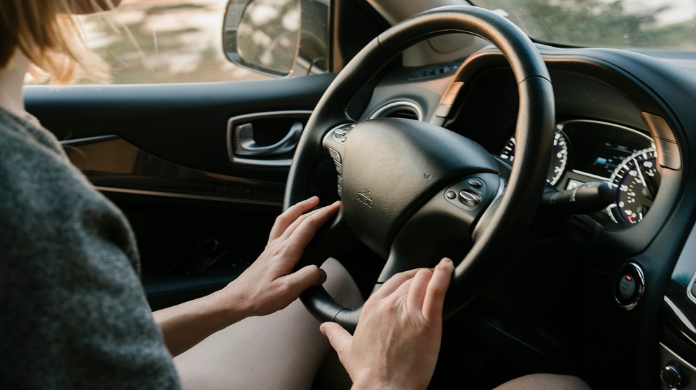 Weibliche hand drückt die hupe am lenkrad eines modernen autos